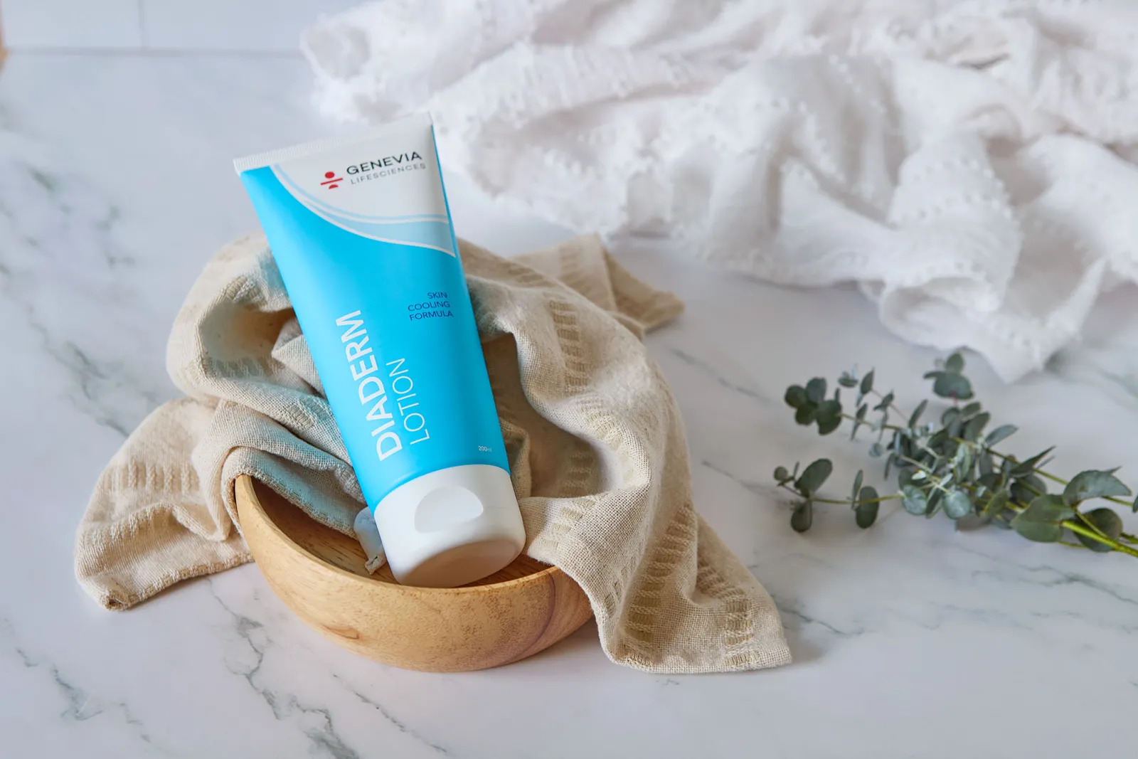 Diaderm Lotion i en træskål med eukalyptus på marmor