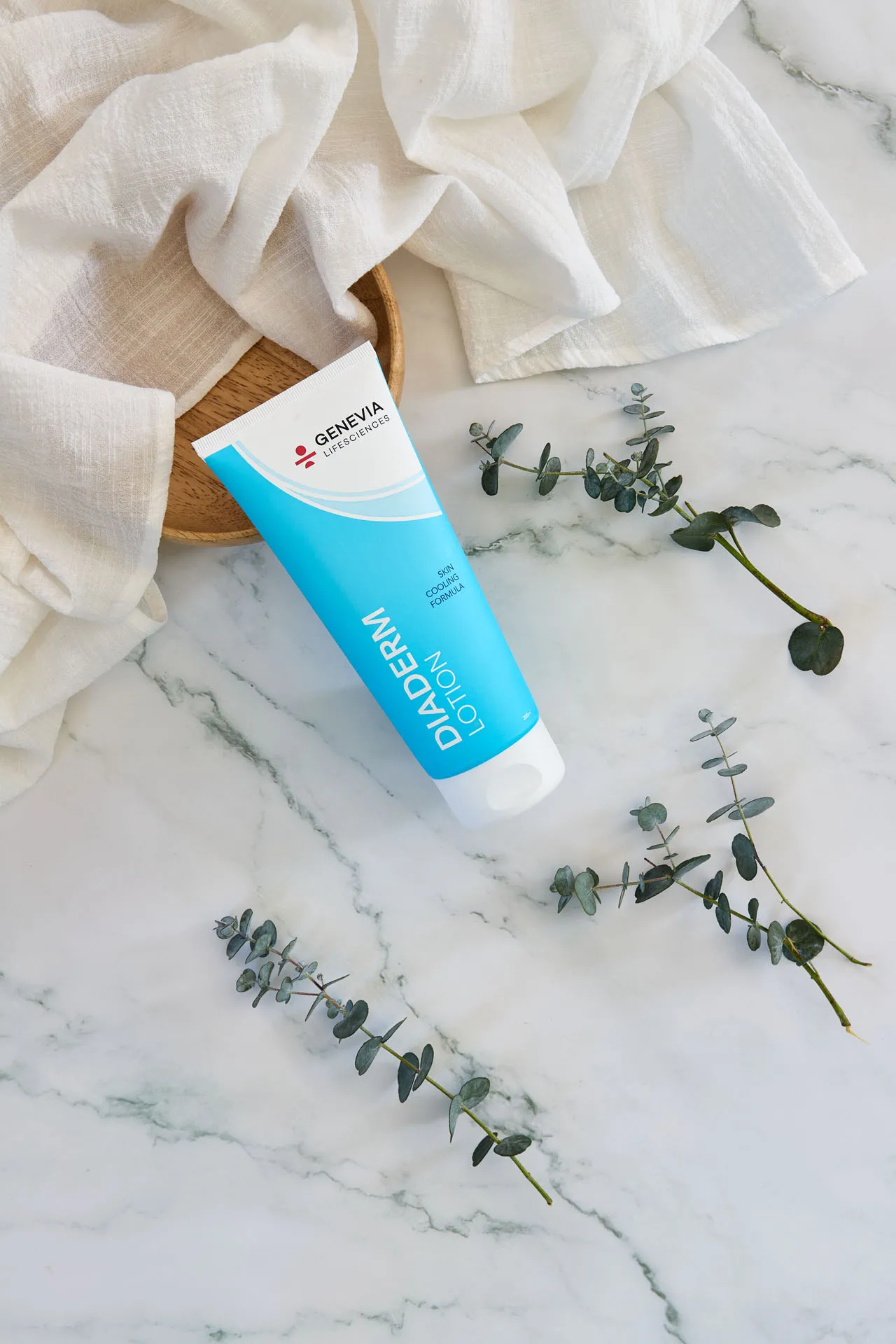Diaderm Lotion med eukalyptus på hvidt stof og marmor